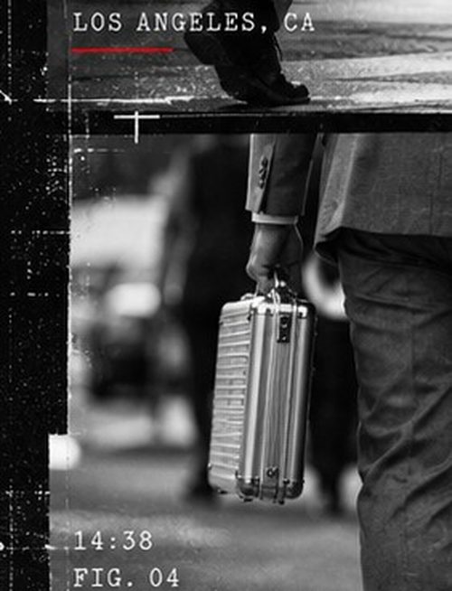 A man in a suit carrying a silver case, seen from behind on a Los Angeles street