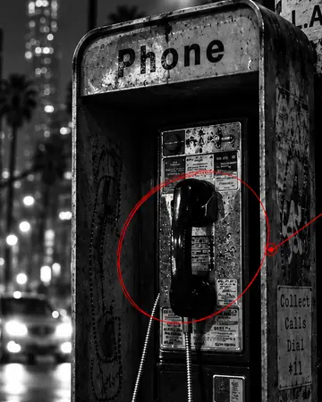 A weathered public payphone on a rain-wet Los Angeles street at night.